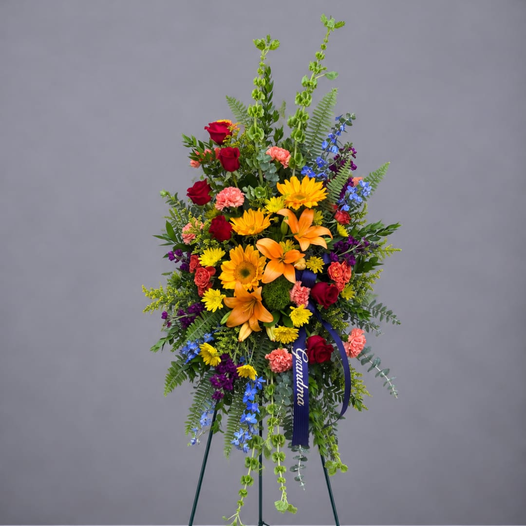 Tall standing floral spray with mixed bright flowers on a tripod easel