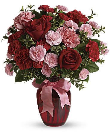 Red roses and pink carnations in a red vase with a pink ribbon