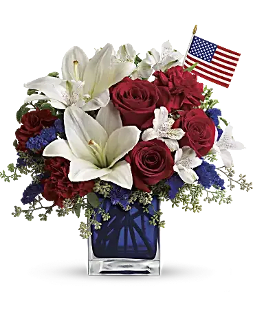 Red roses and white lilies in a glass vase with a small American flag