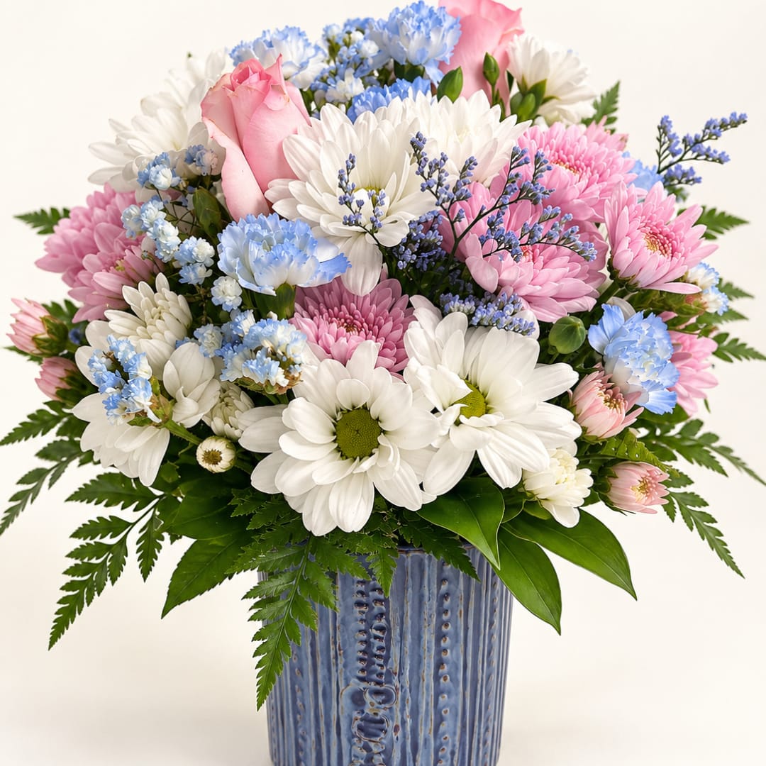 Pink and white daisies with blue accents in a blue ceramic vase