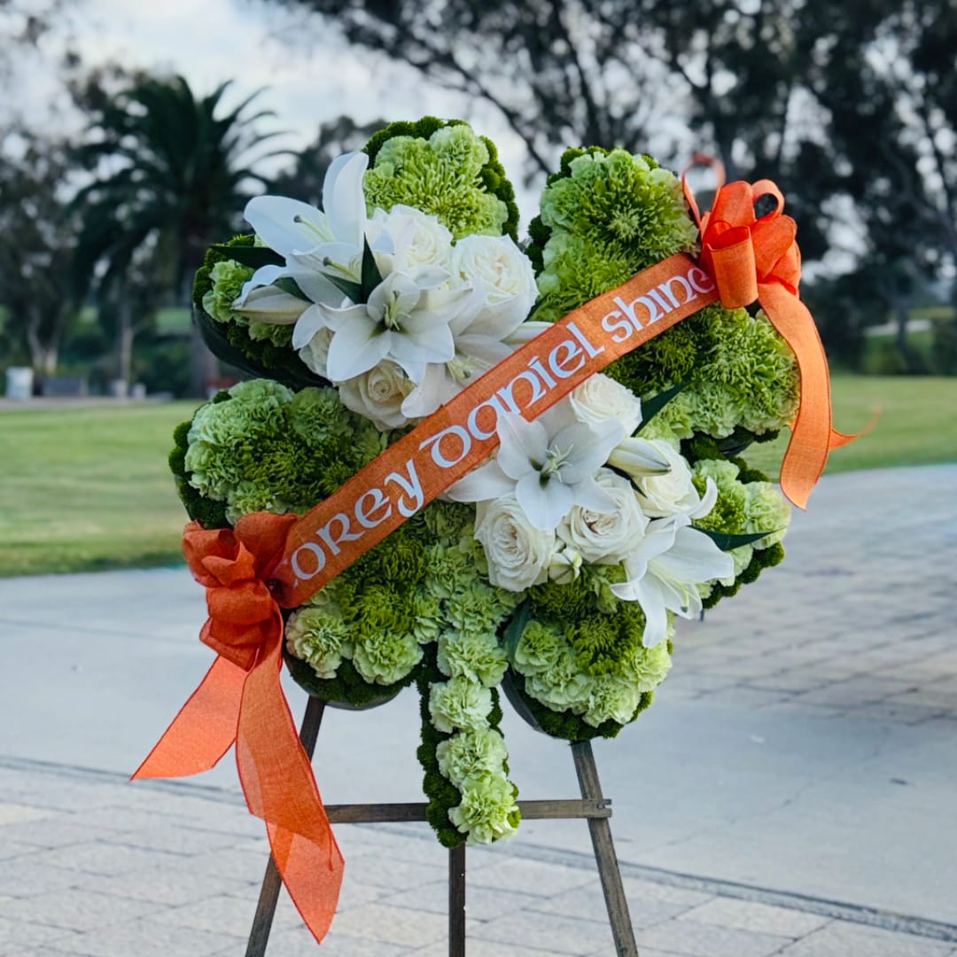Green and white funeral wreath with lilies and roses on an easel