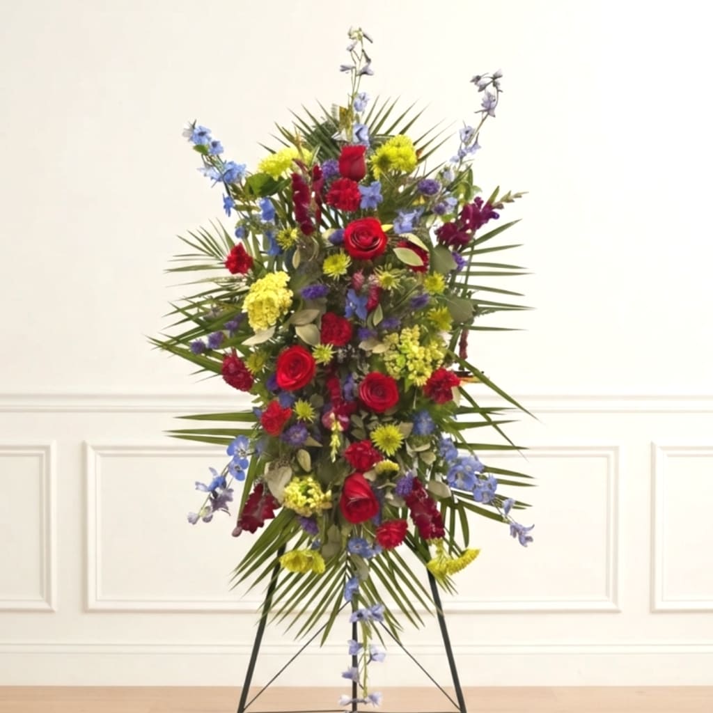 Tall standing floral spray with red roses, blue flowers, and yellow blooms