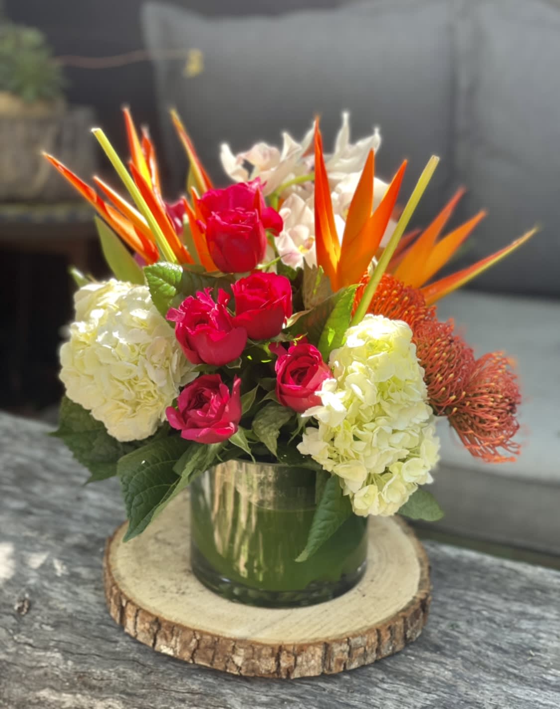 Bouquet of pink roses, white hydrangeas, and orange tropical blooms in a glass vase