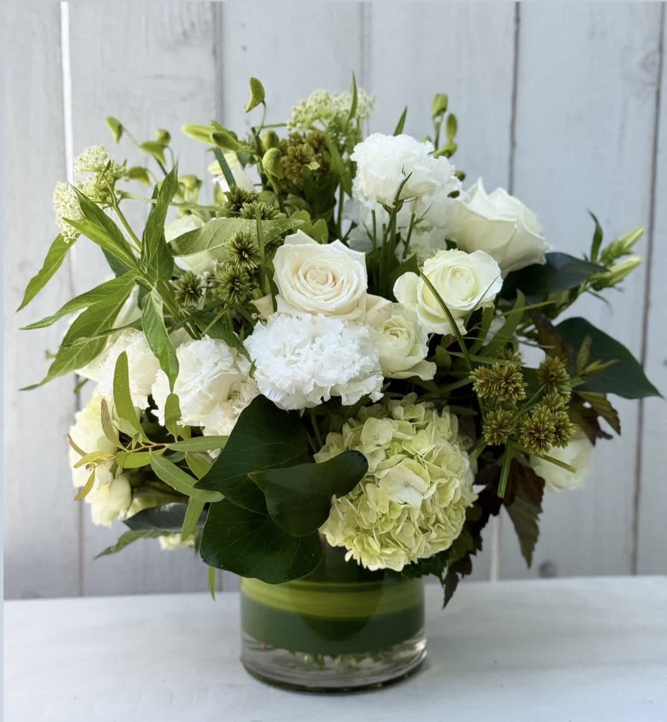 White roses and hydrangea arranged in a glass vase