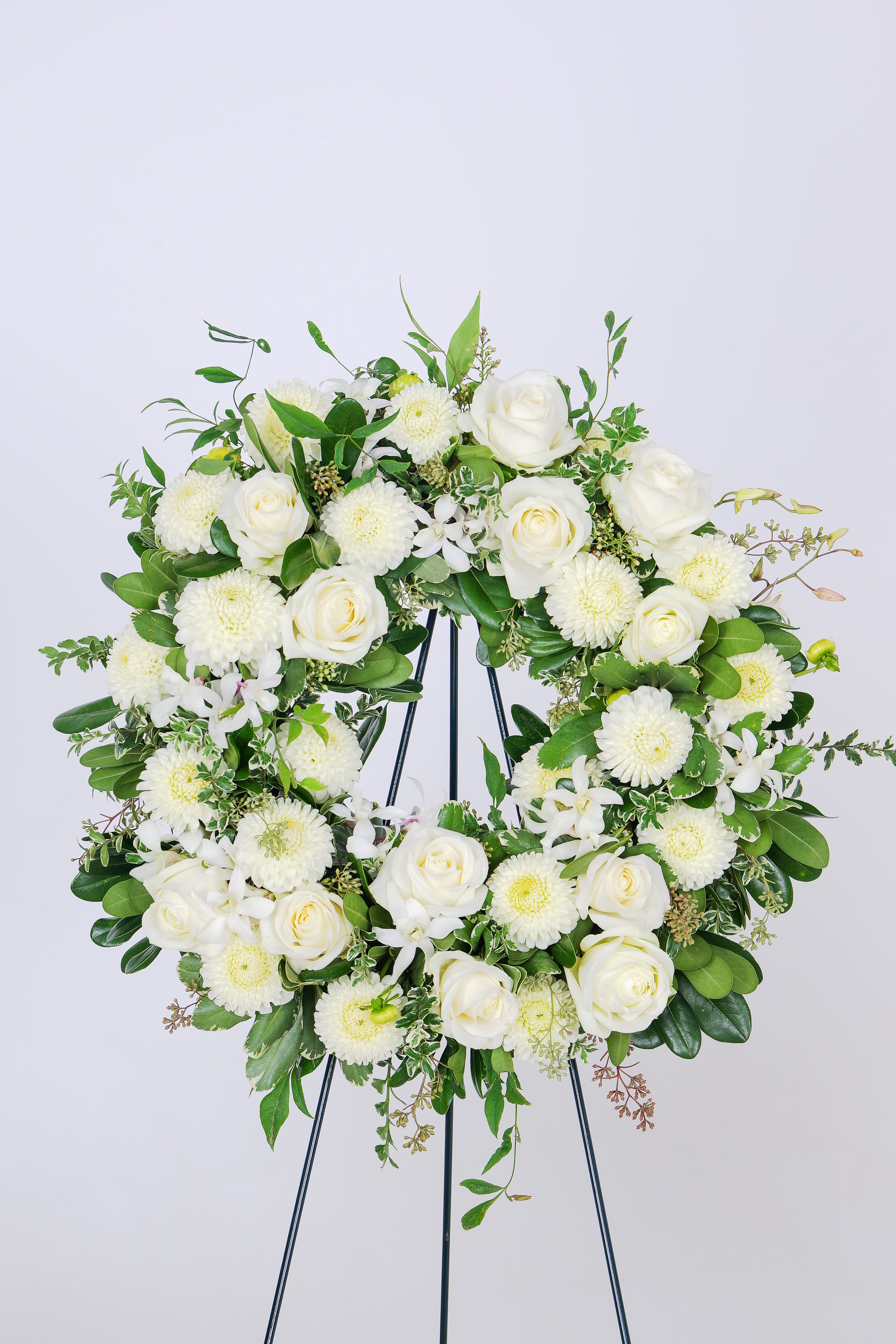 White rose and chrysanthemum wreath on a black stand