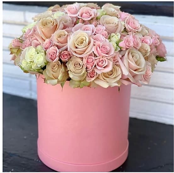 Pink and cream roses arranged in a round pink box