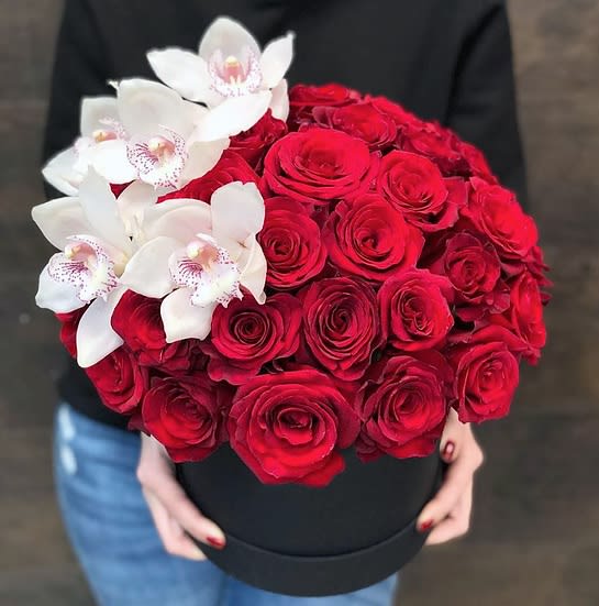 Red roses with white orchids in a black hat box