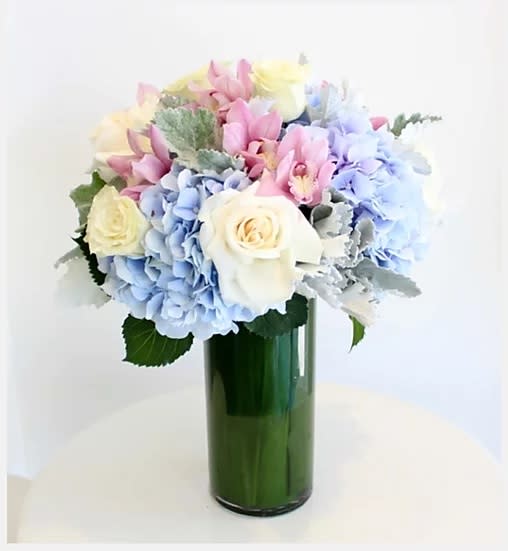 Pastel bouquet of hydrangeas and roses in a green glass vase