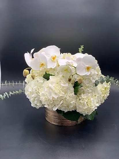 White orchids and hydrangeas in a low woven basket