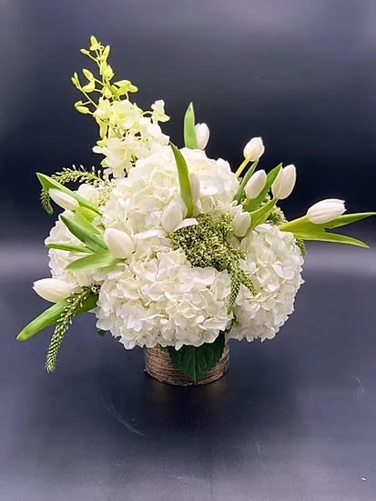 White floral arrangement with tulips and hydrangeas in a woven basket