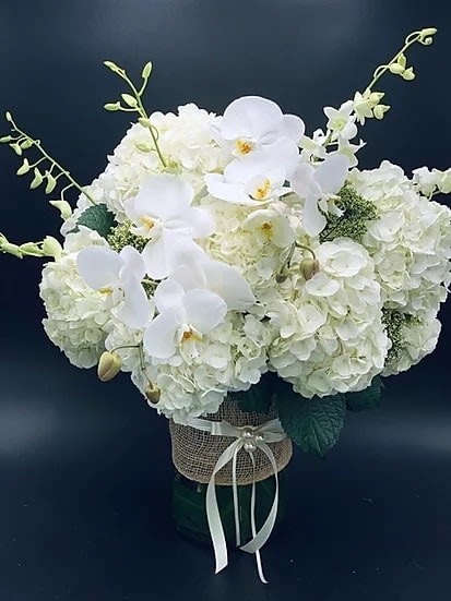 White hydrangea and orchid arrangement in a wrapped vase