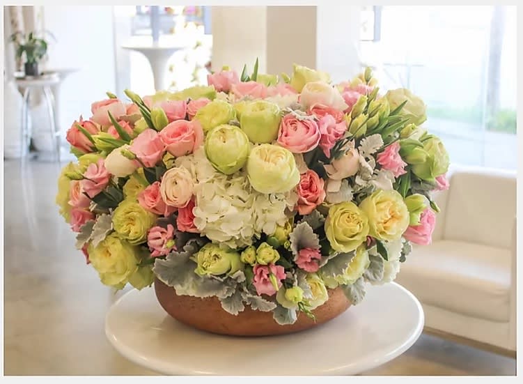 Large pastel flower arrangement in a low round bowl