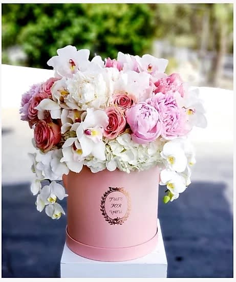 Pink and white floral arrangement in a round pink box