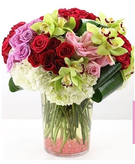 Bouquet of red and pink roses with green orchids in a glass vase