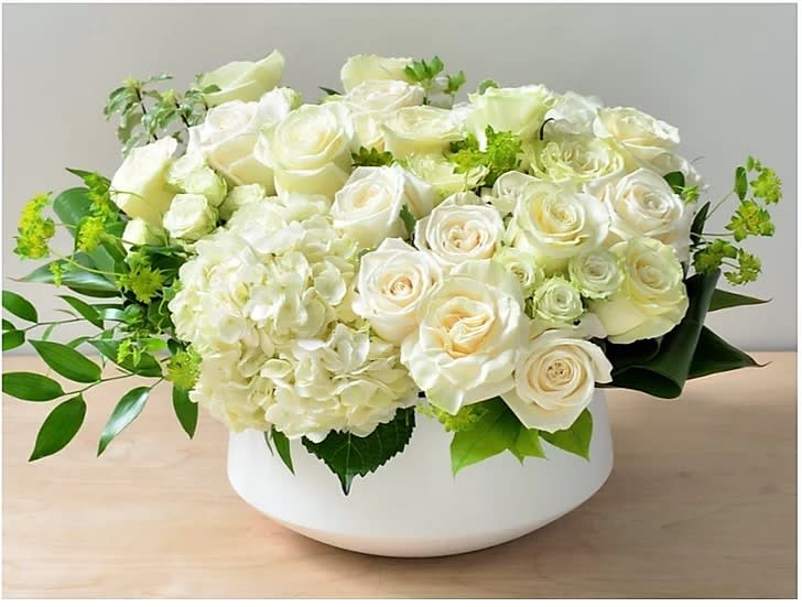 White roses and hydrangeas arranged in a low white bowl