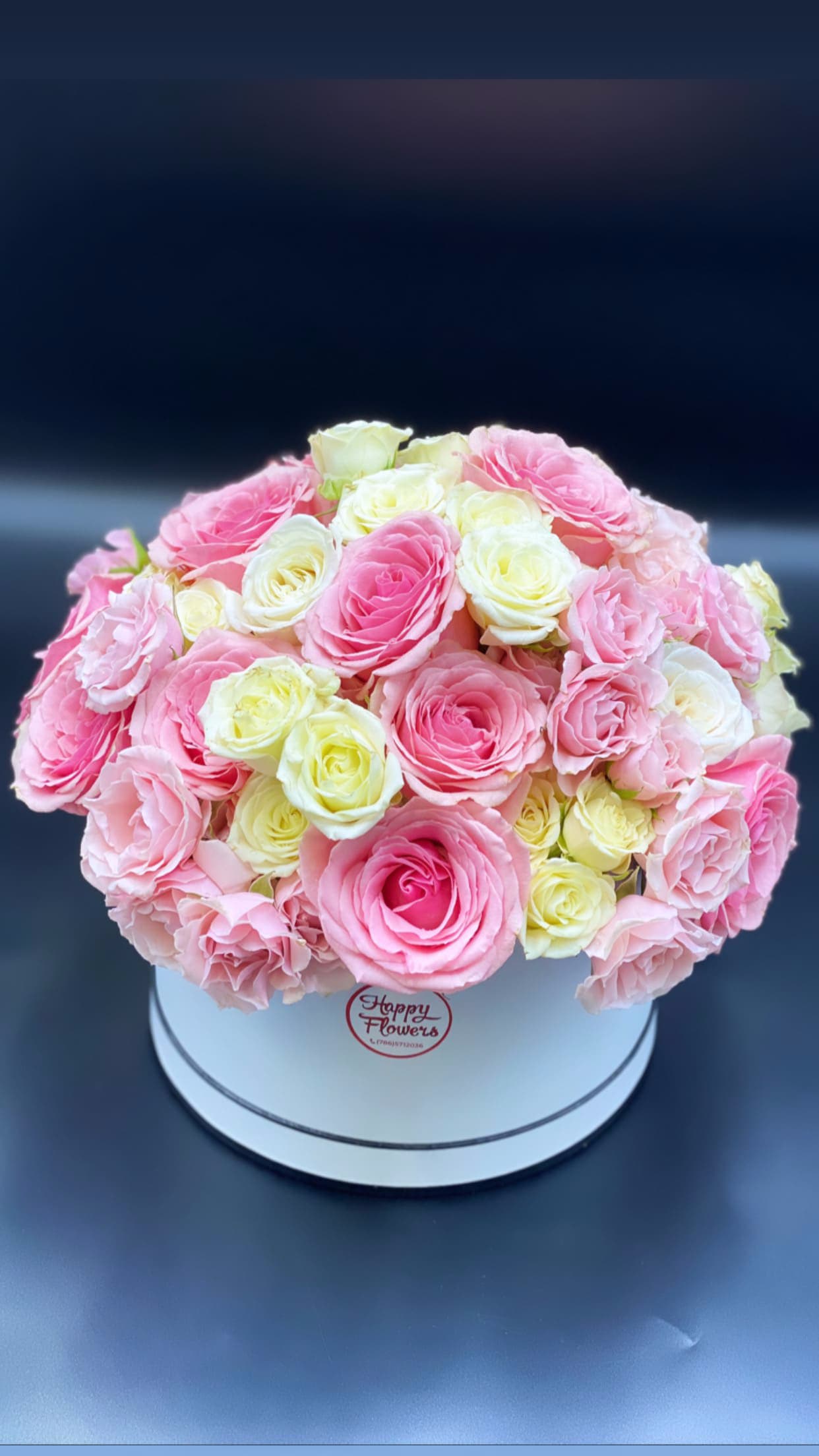 Pink and white roses arranged in a round white box