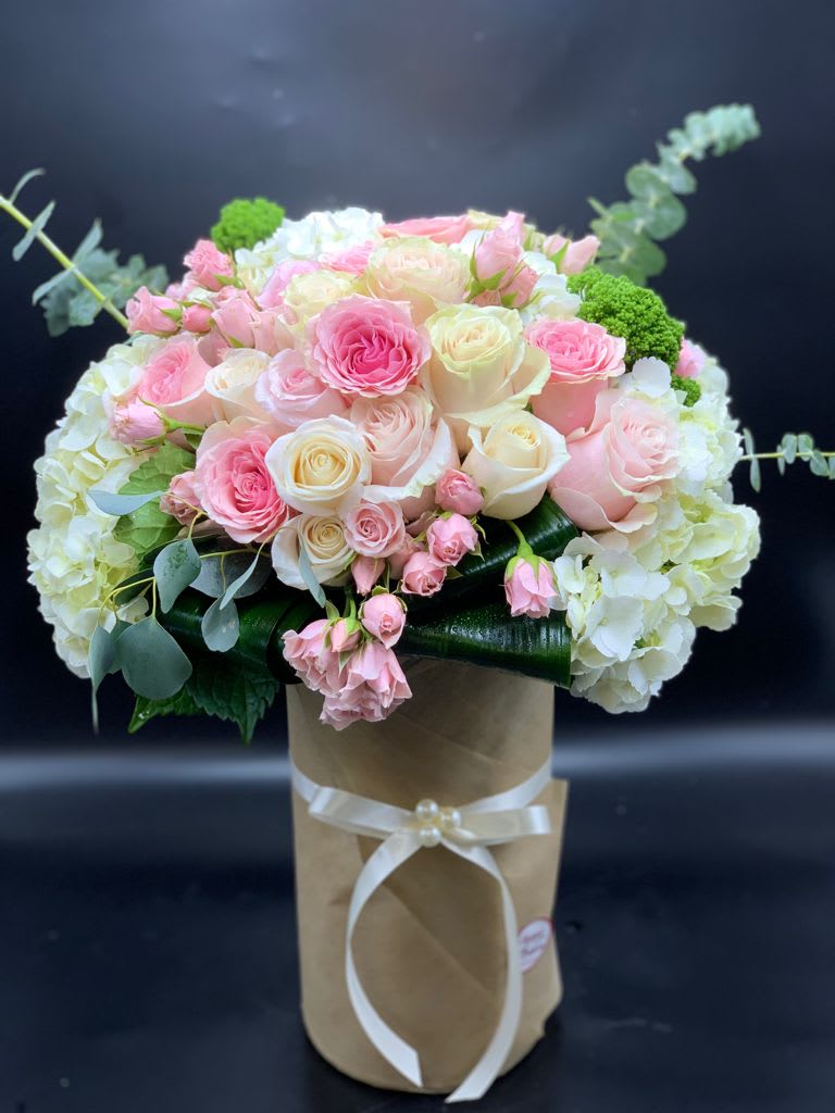 Pink and white rose bouquet in a brown paper wrap with a ribbon