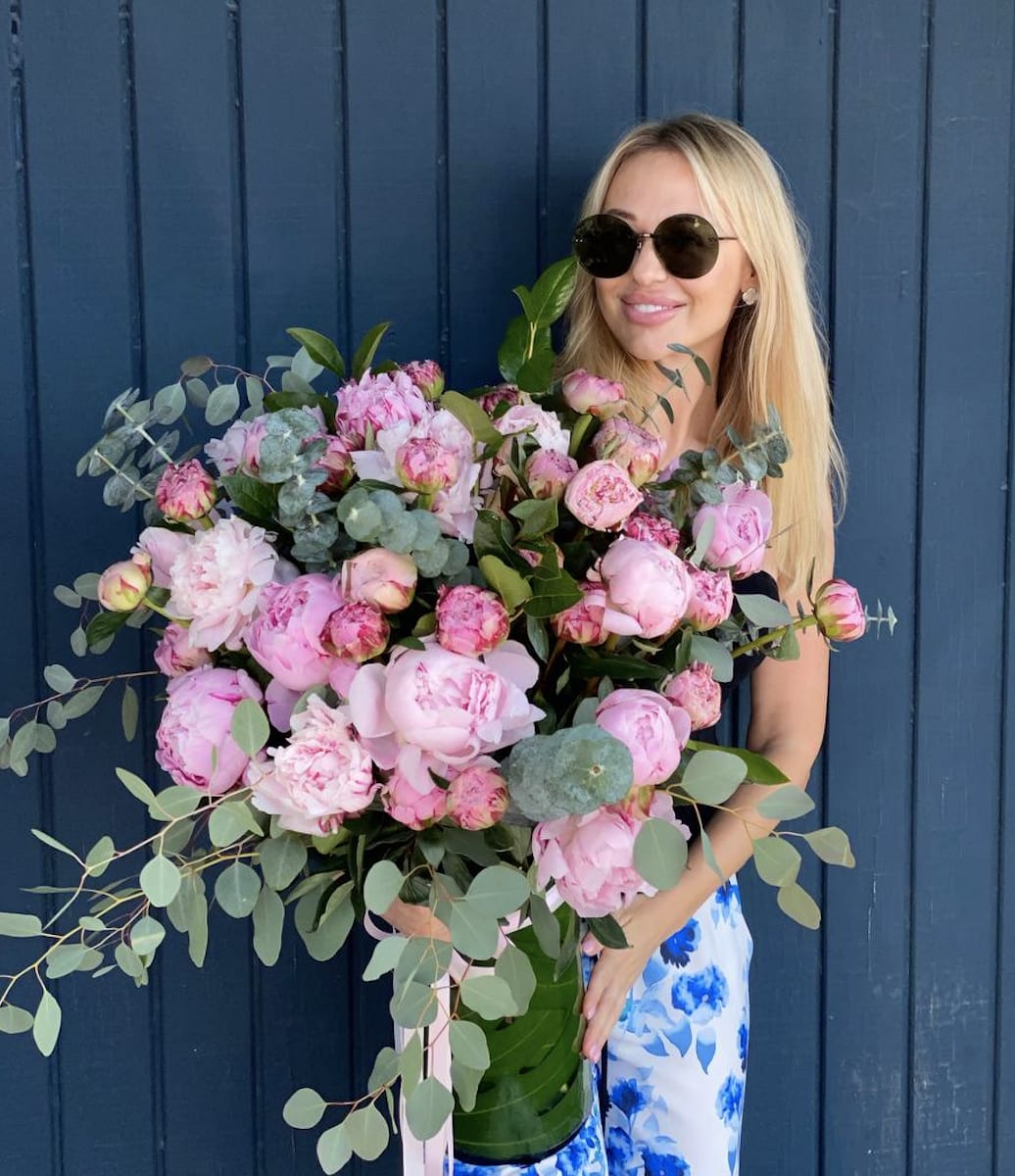 Woman holding a large bouquet of pink peonies and eucalyptus