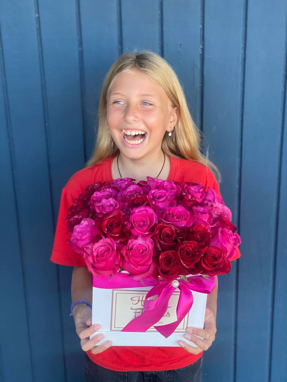 Girl holding a box of pink and red roses with a ribbon