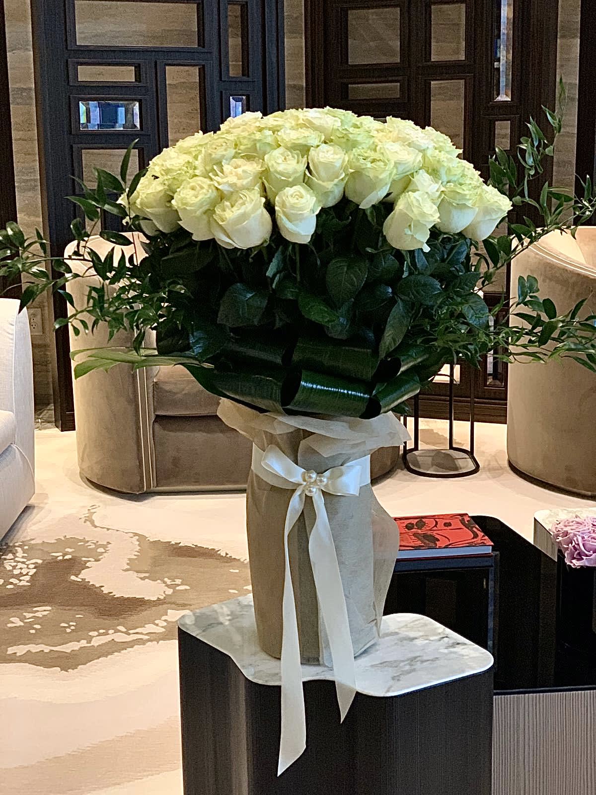 Large bouquet of white roses in a wrapped vase with a ribbon