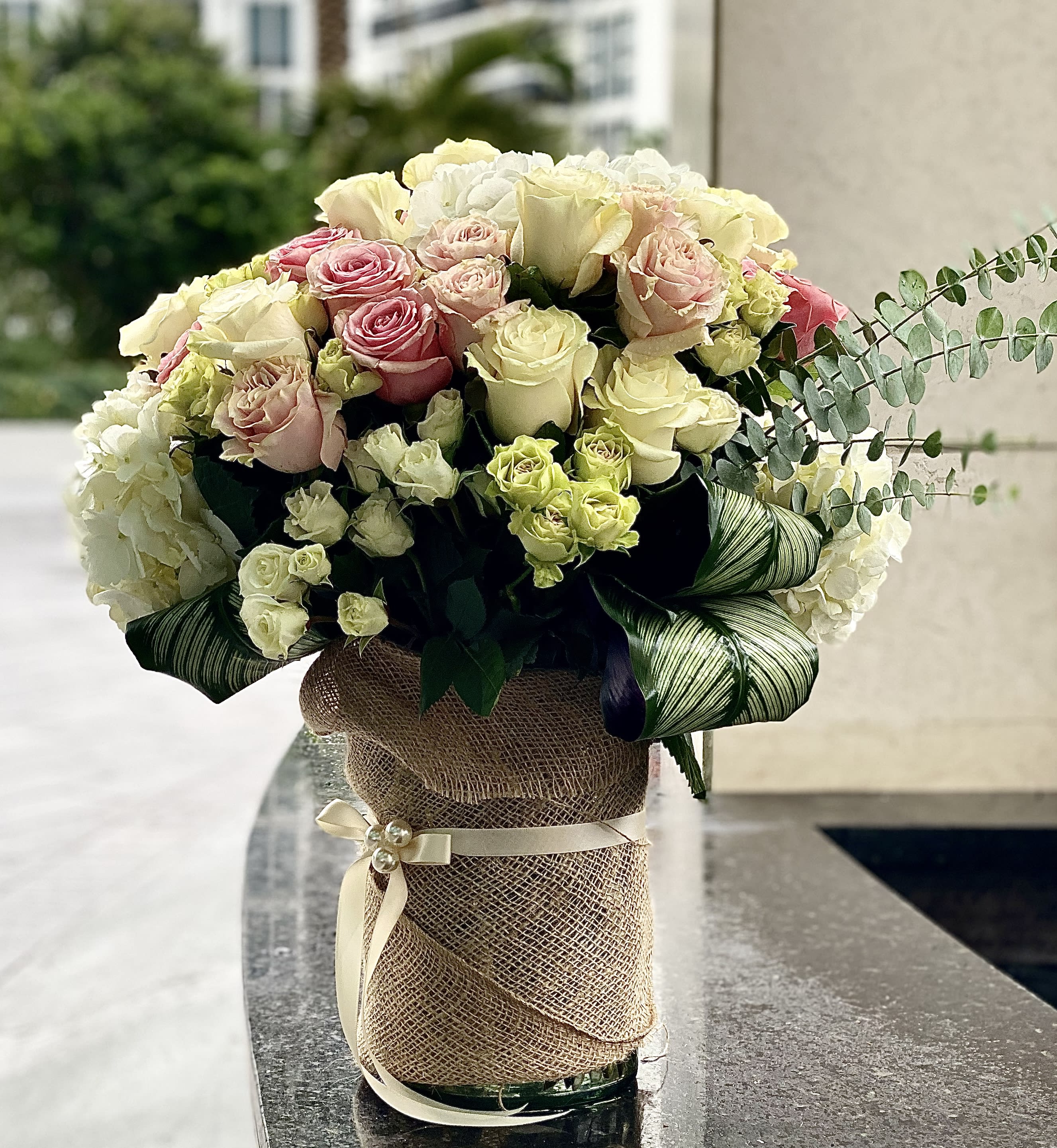 Bouquet of pink and cream roses in a burlap-wrapped vase