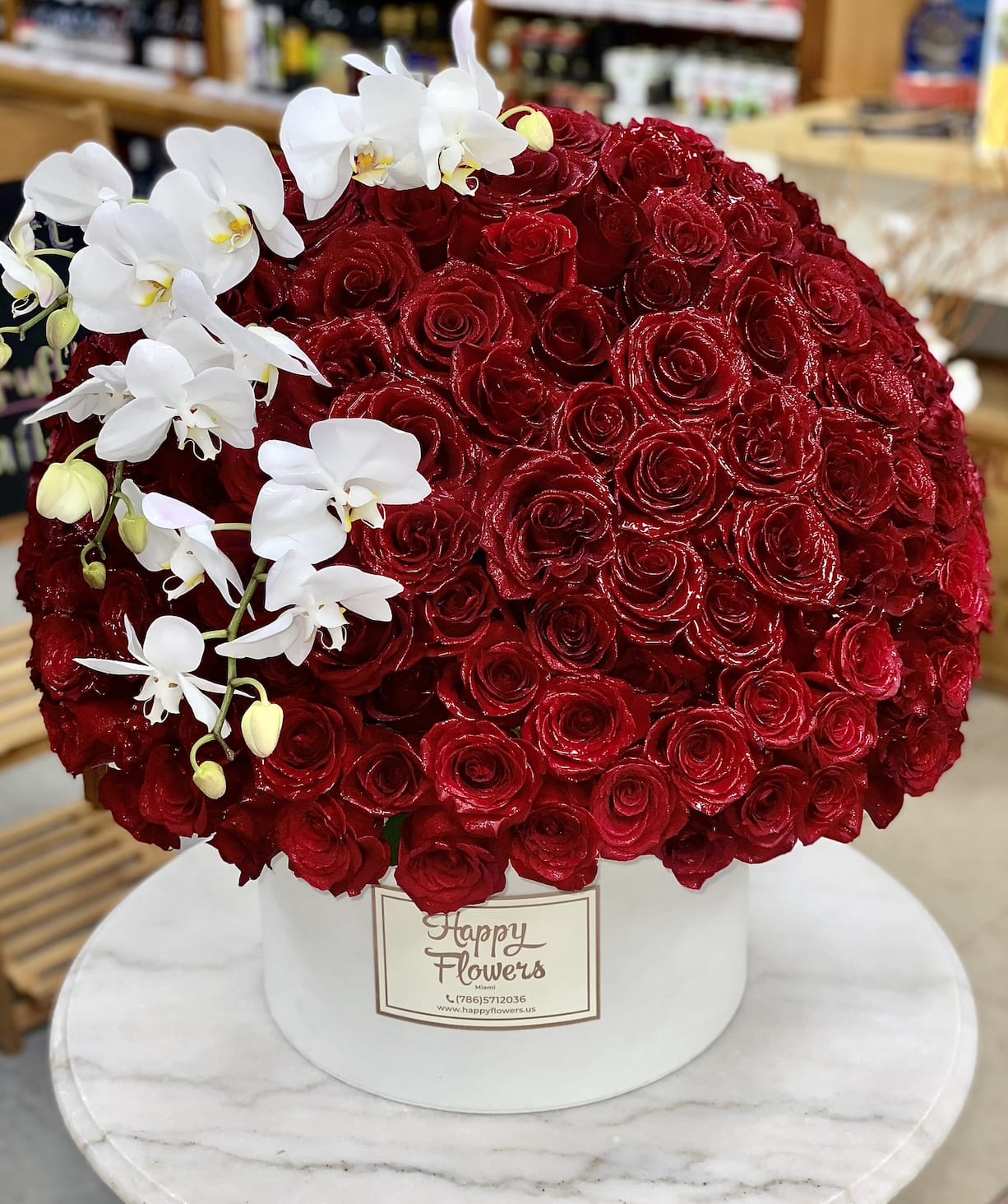 Large red rose arrangement with white orchids in a white hat box