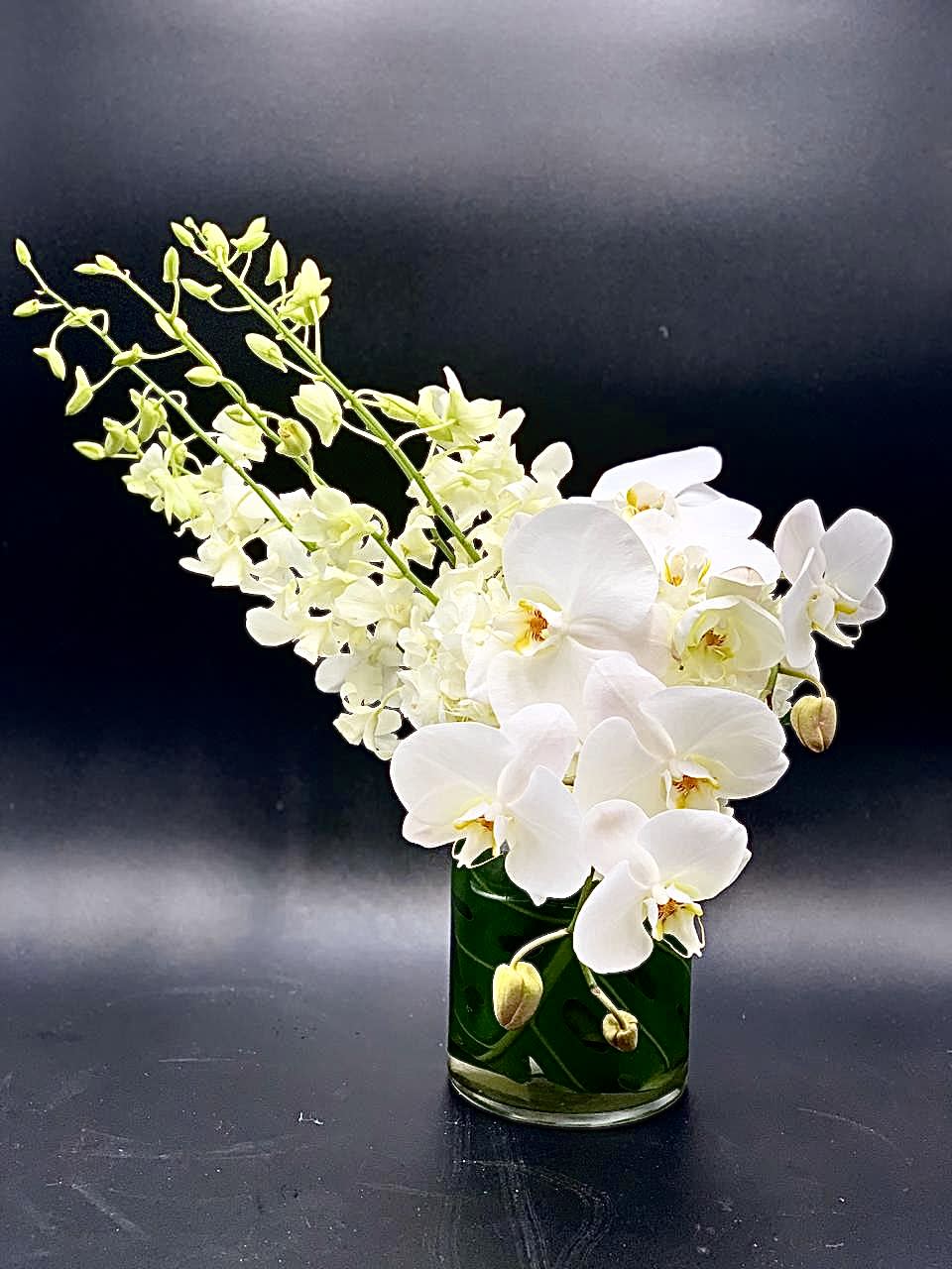 White orchids arranged in a green glass vase