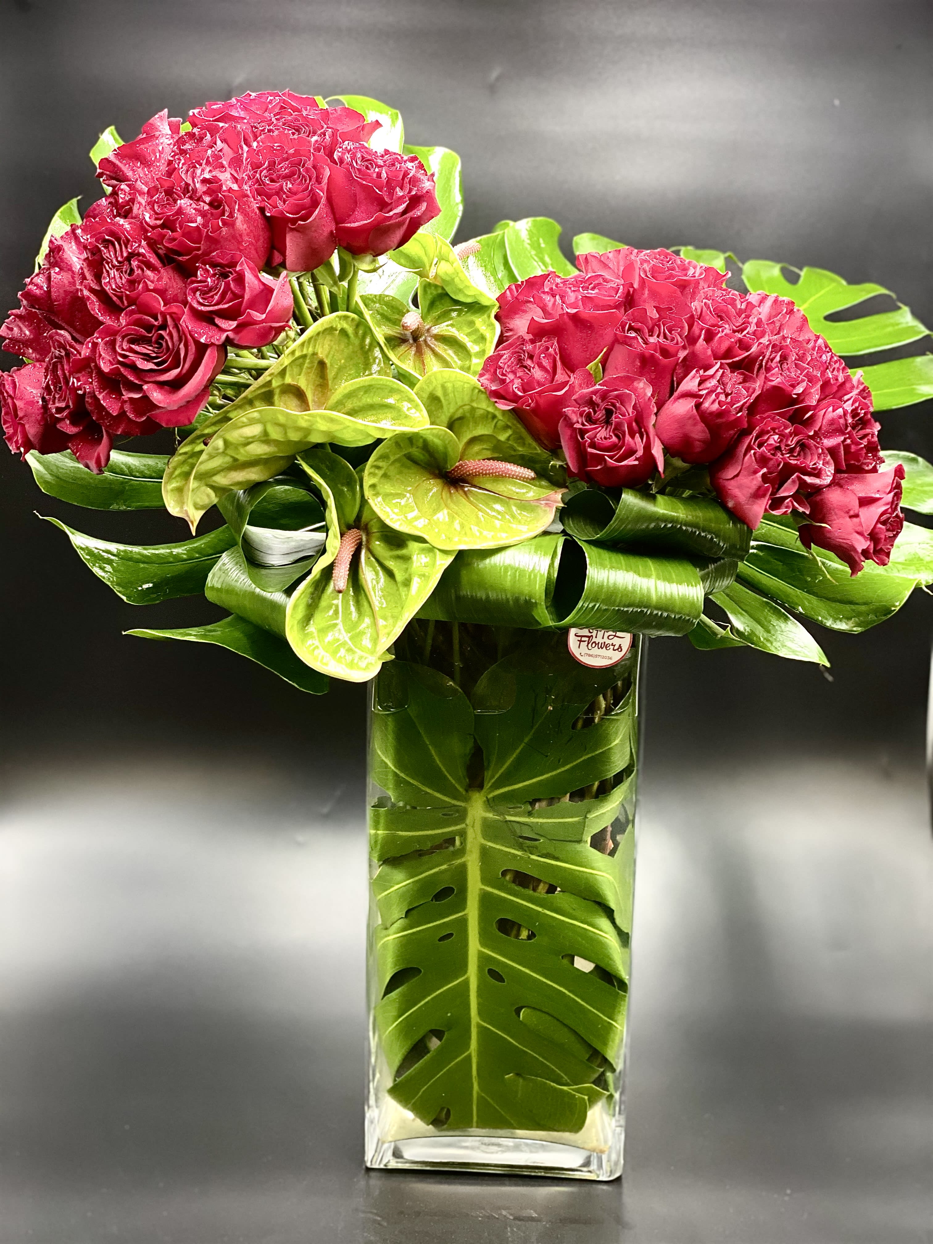 Pink rose bouquet with green anthuriums in a tall glass vase