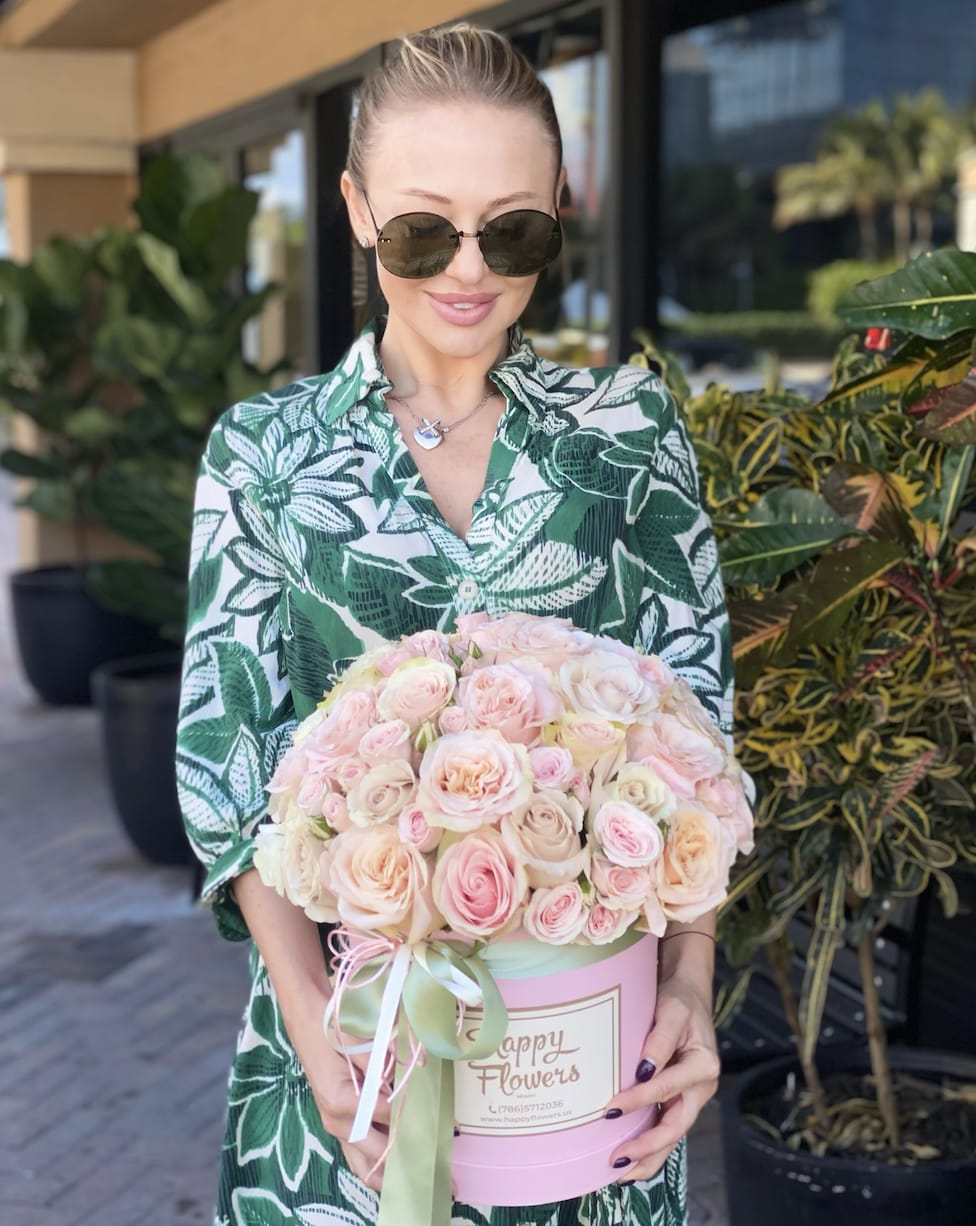 Woman holding a pink box of pale pink roses