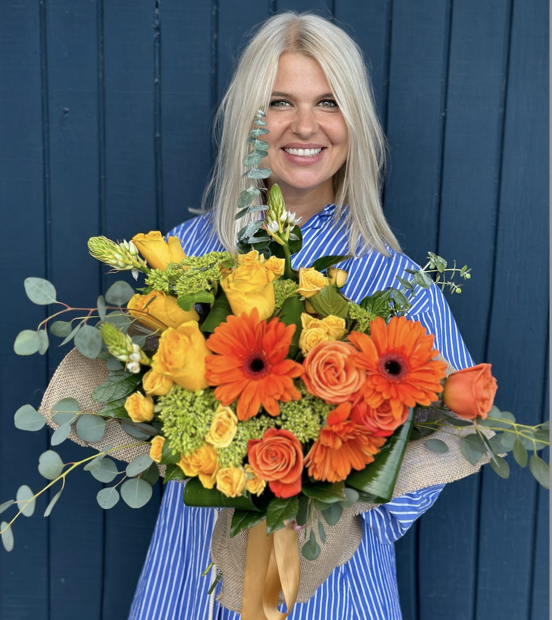 Woman holding a bouquet of orange and yellow flowers