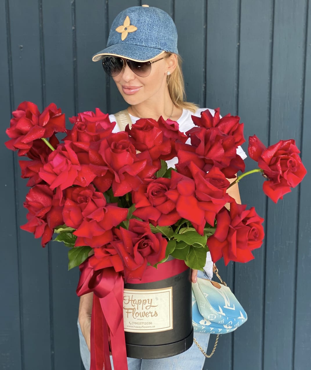 Woman holding a large box of red roses with a ribbon