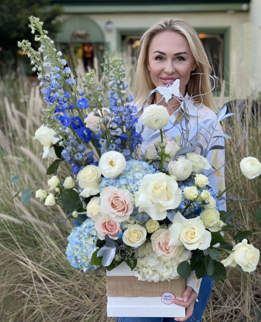 Woman holding a large bouquet of white, pink, and blue flowers in a box