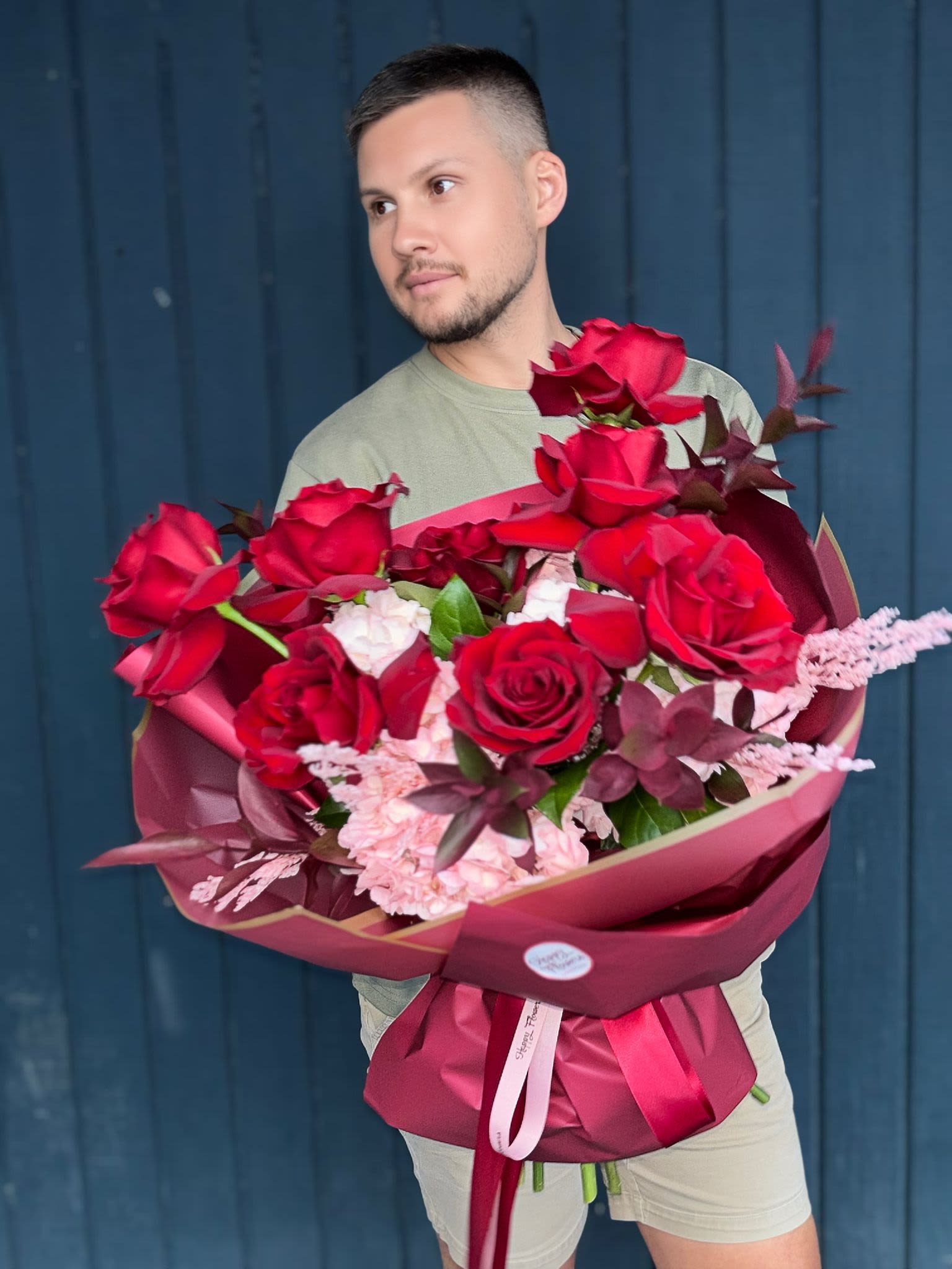 Man holding a large bouquet of red roses and pink flowers