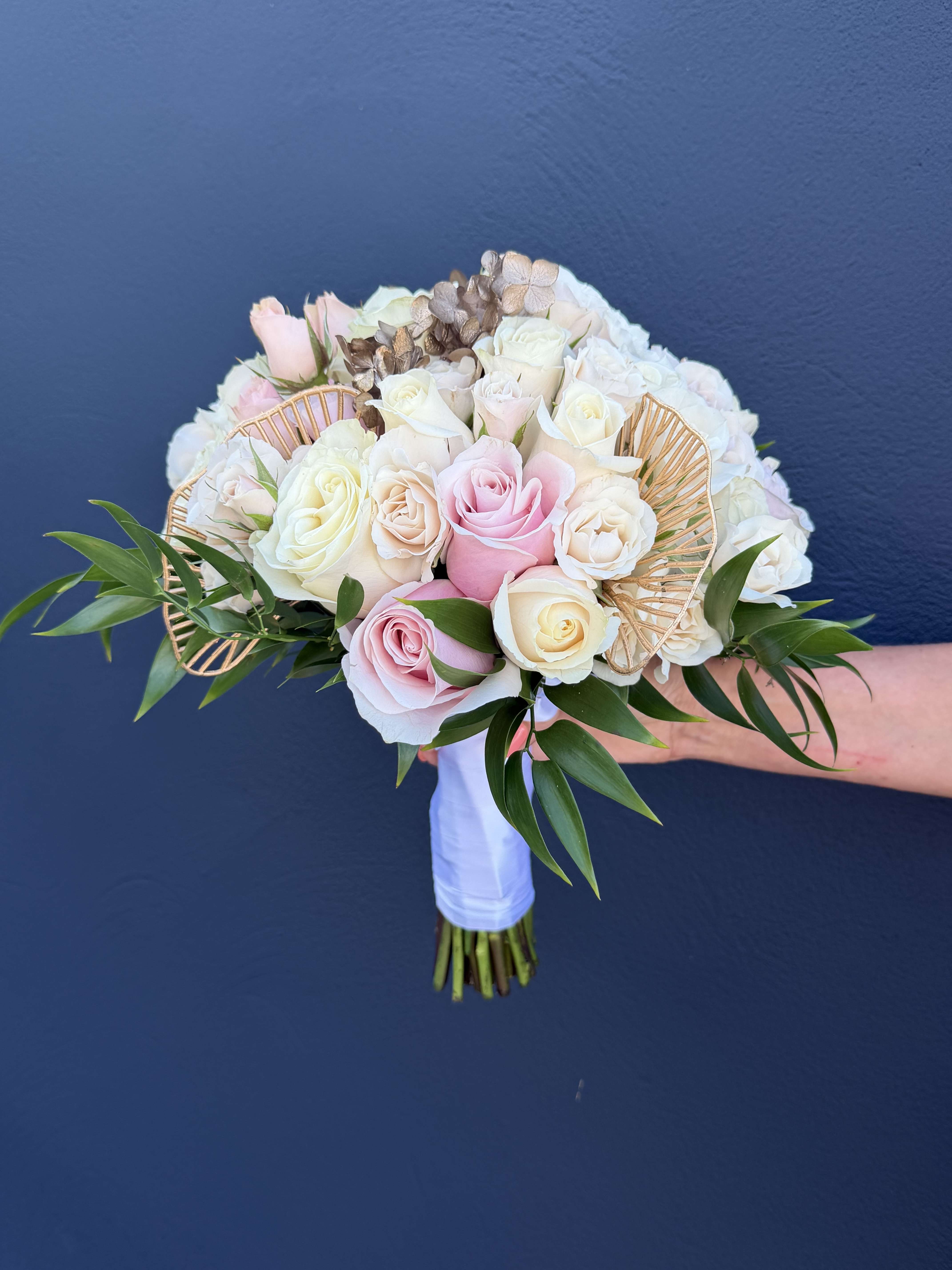 Wedding bouquet of pink and white roses with gold fan accents