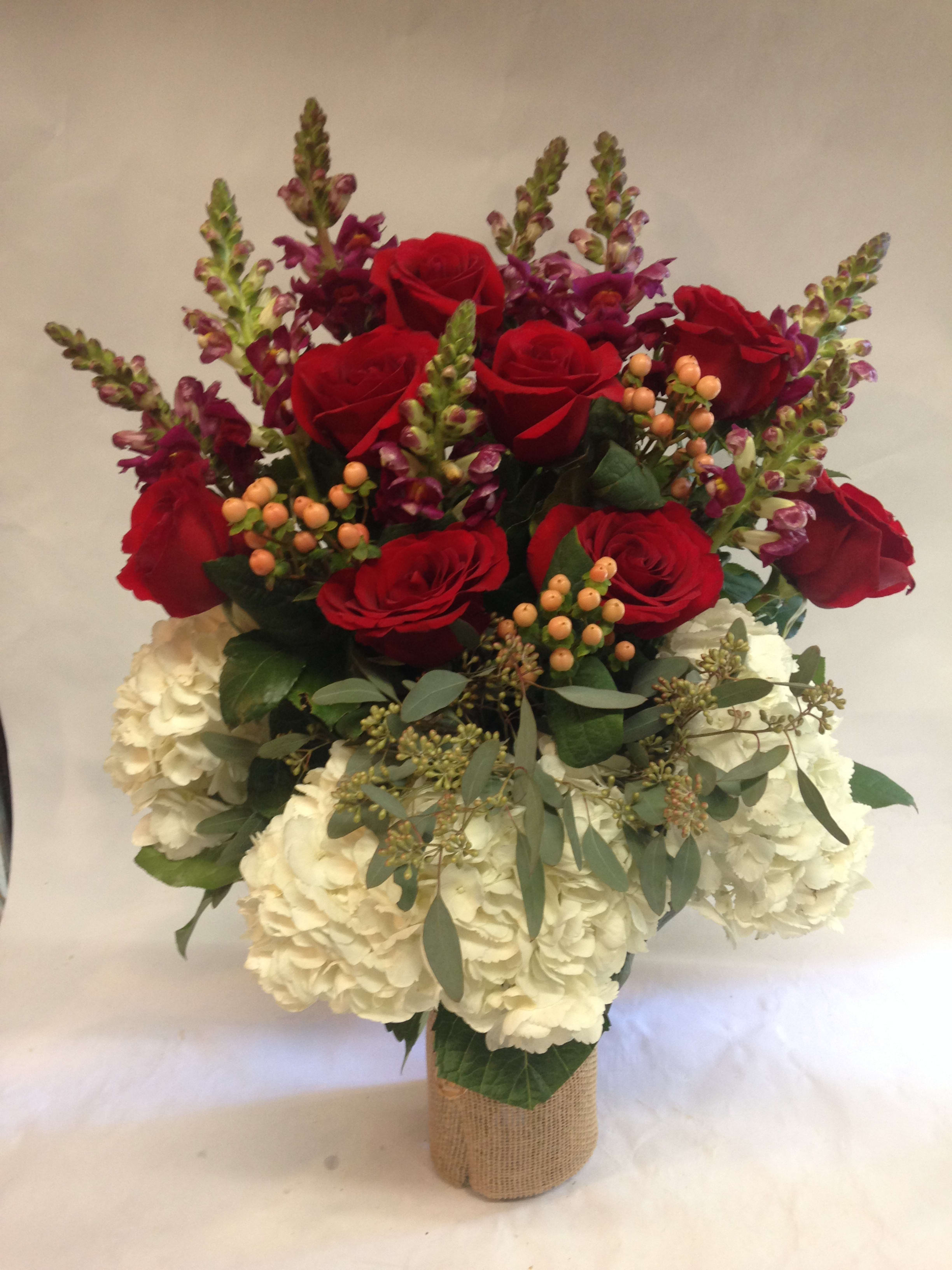 Bouquet of red roses and white hydrangeas in a burlap-wrapped vase