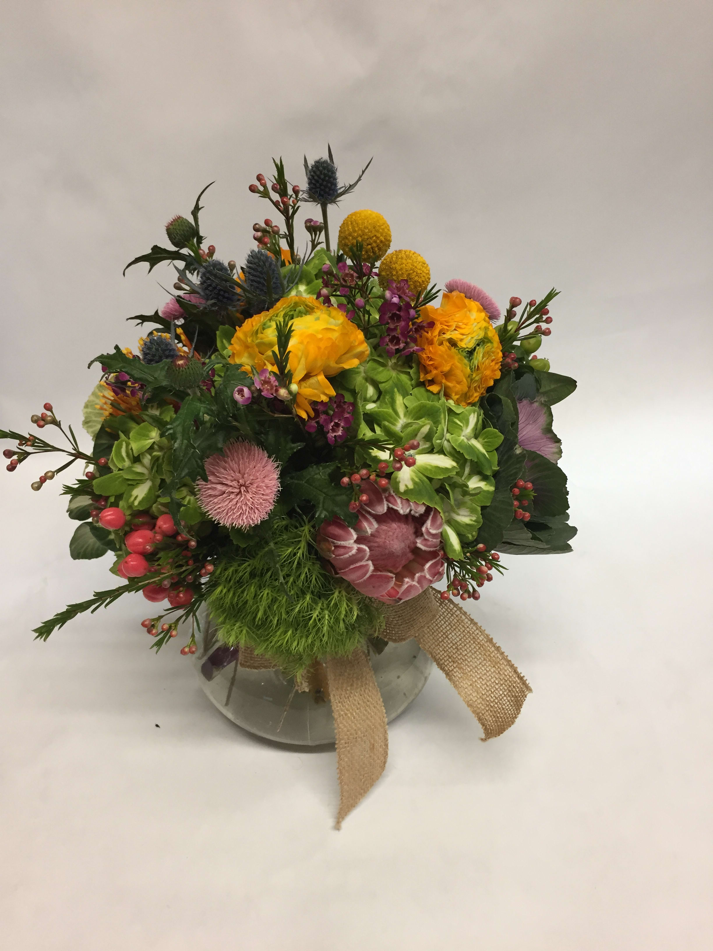 Mixed bouquet in a glass vase with yellow, pink, and purple blooms