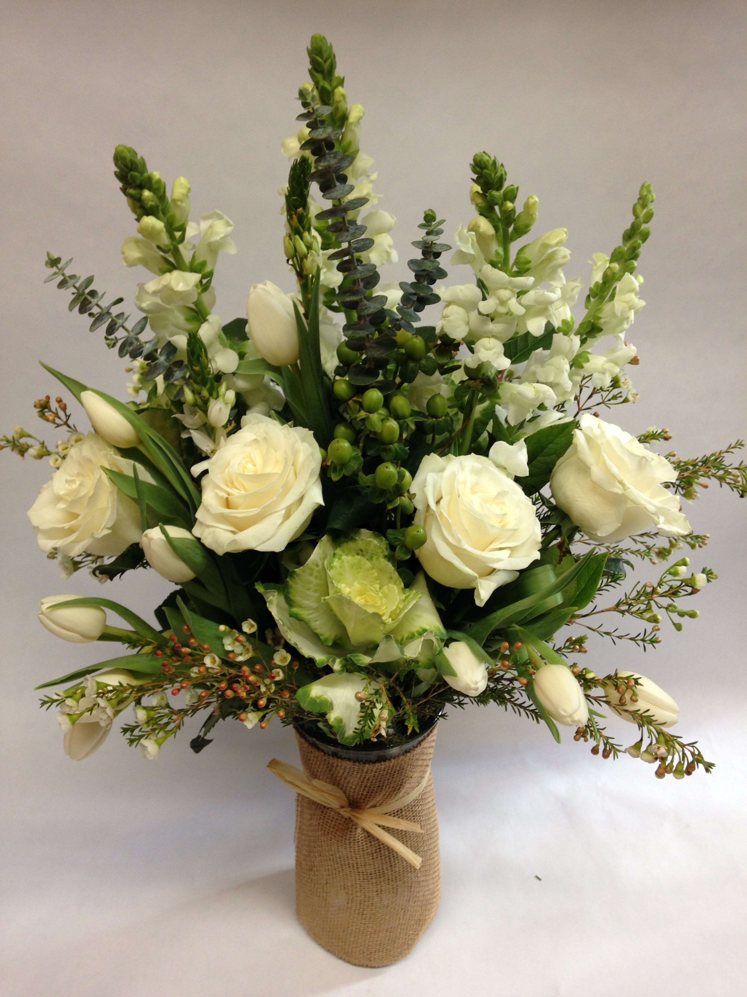 White roses and tulips arranged in a burlap-wrapped vase