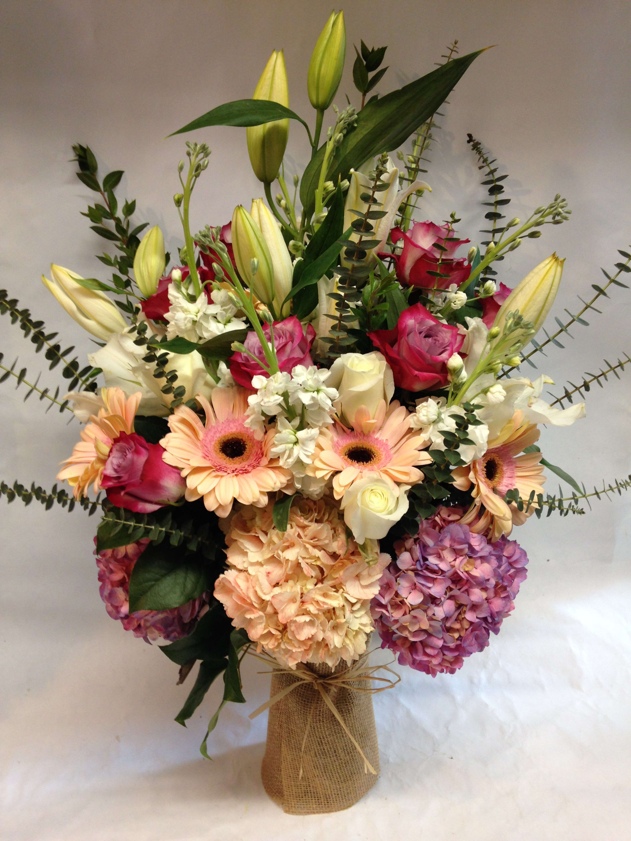 Peach Elegance - This lavish peach arrangement is composed of peach gerbera daisies, both lavender and white roses, white casa blanca lilies, peach and lavender hydrangeas, white stock and eucalyptus.  (Some flowers may be subject to change depending on the season. We will contact you with available flower substitutions; please contact us with specific questions if you are concerned with flower availability, thanks!)Featured arrangement: $385.00 (Regular Price)