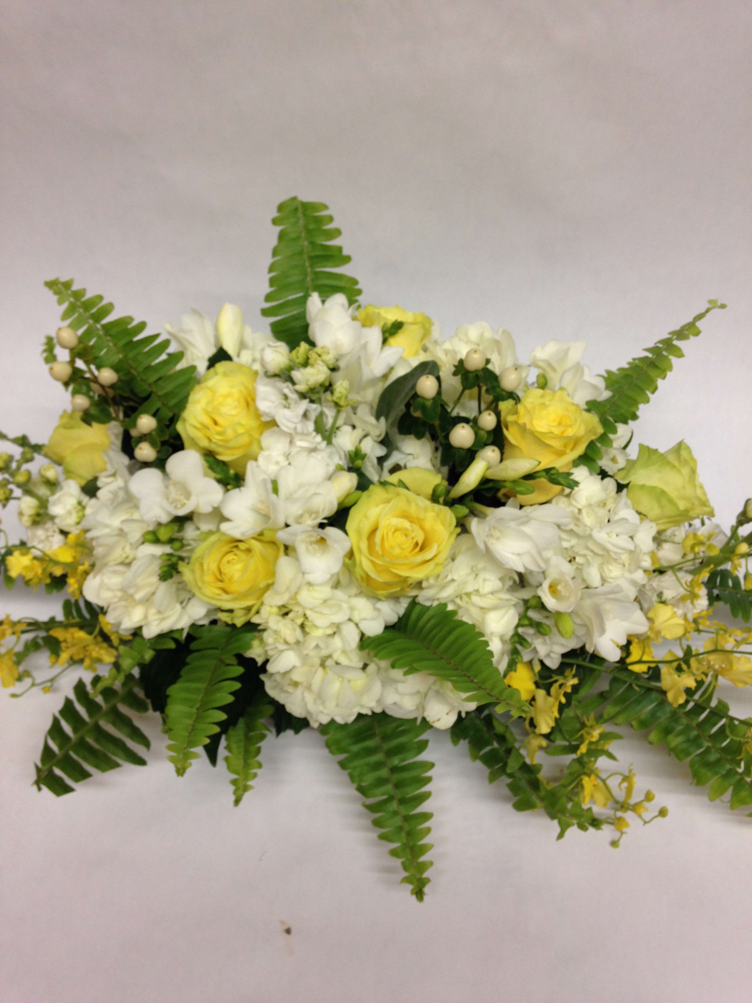Yellow and white floral arrangement with fern fronds