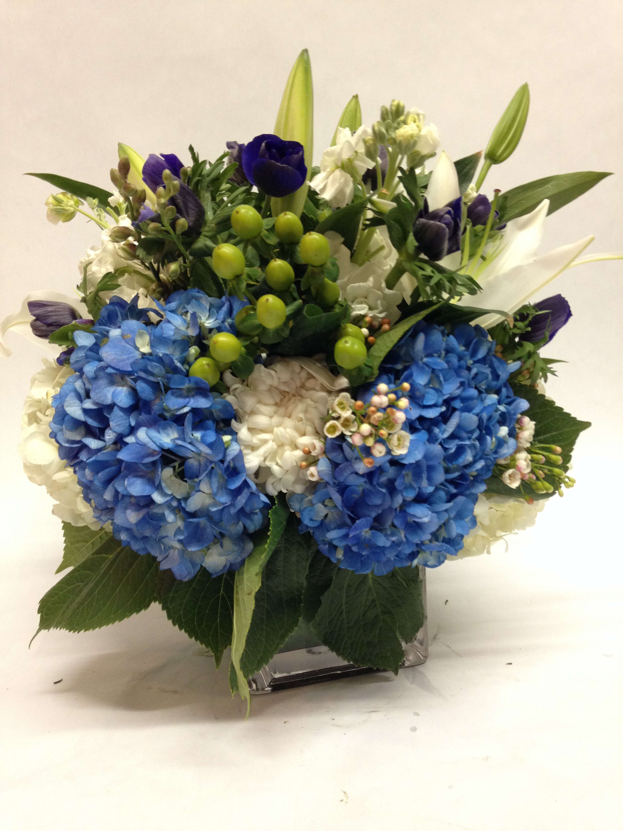 Blue and white floral arrangement in a square glass vase
