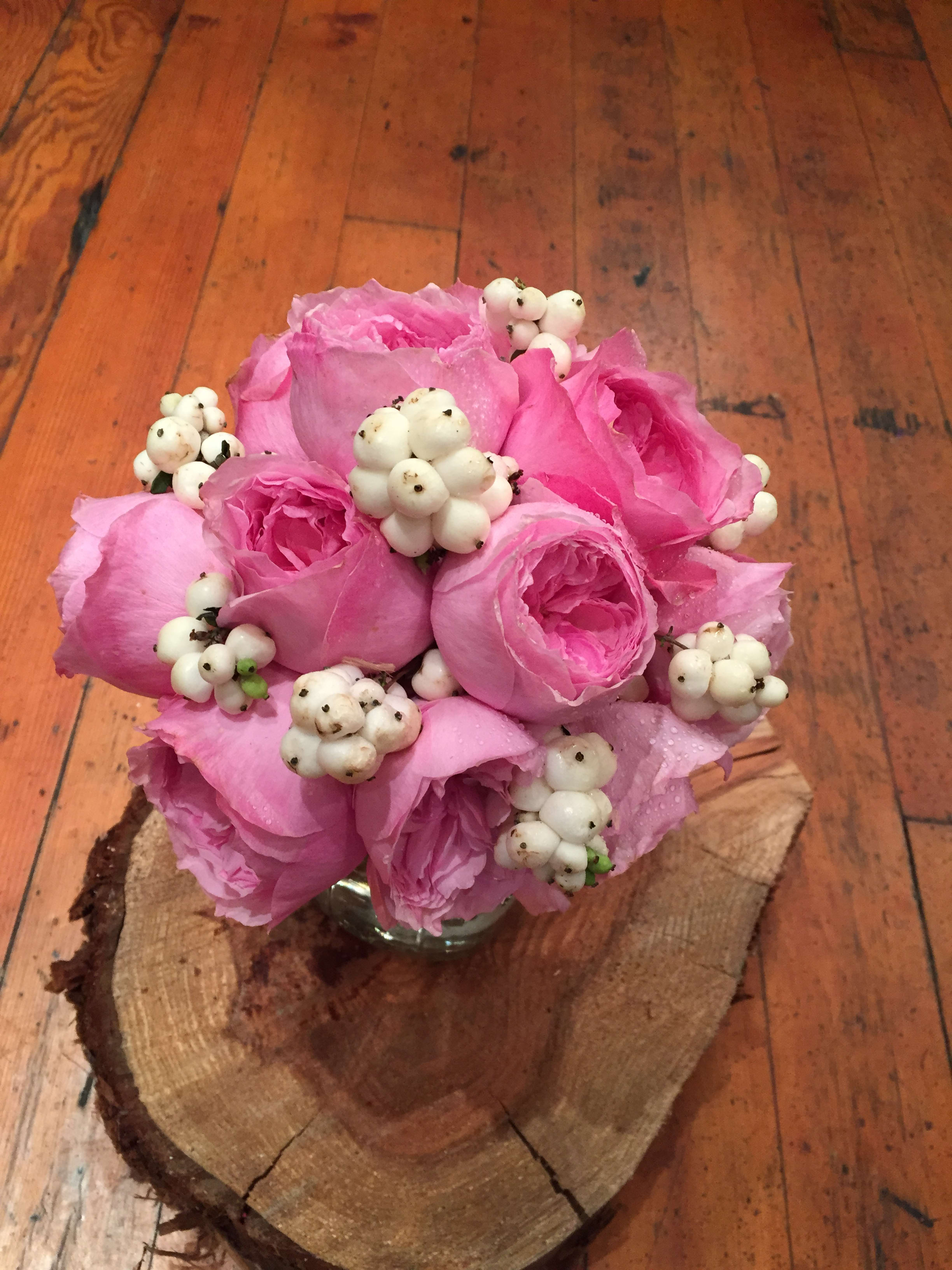 Pink rose bouquet with white berry accents in a small glass vase