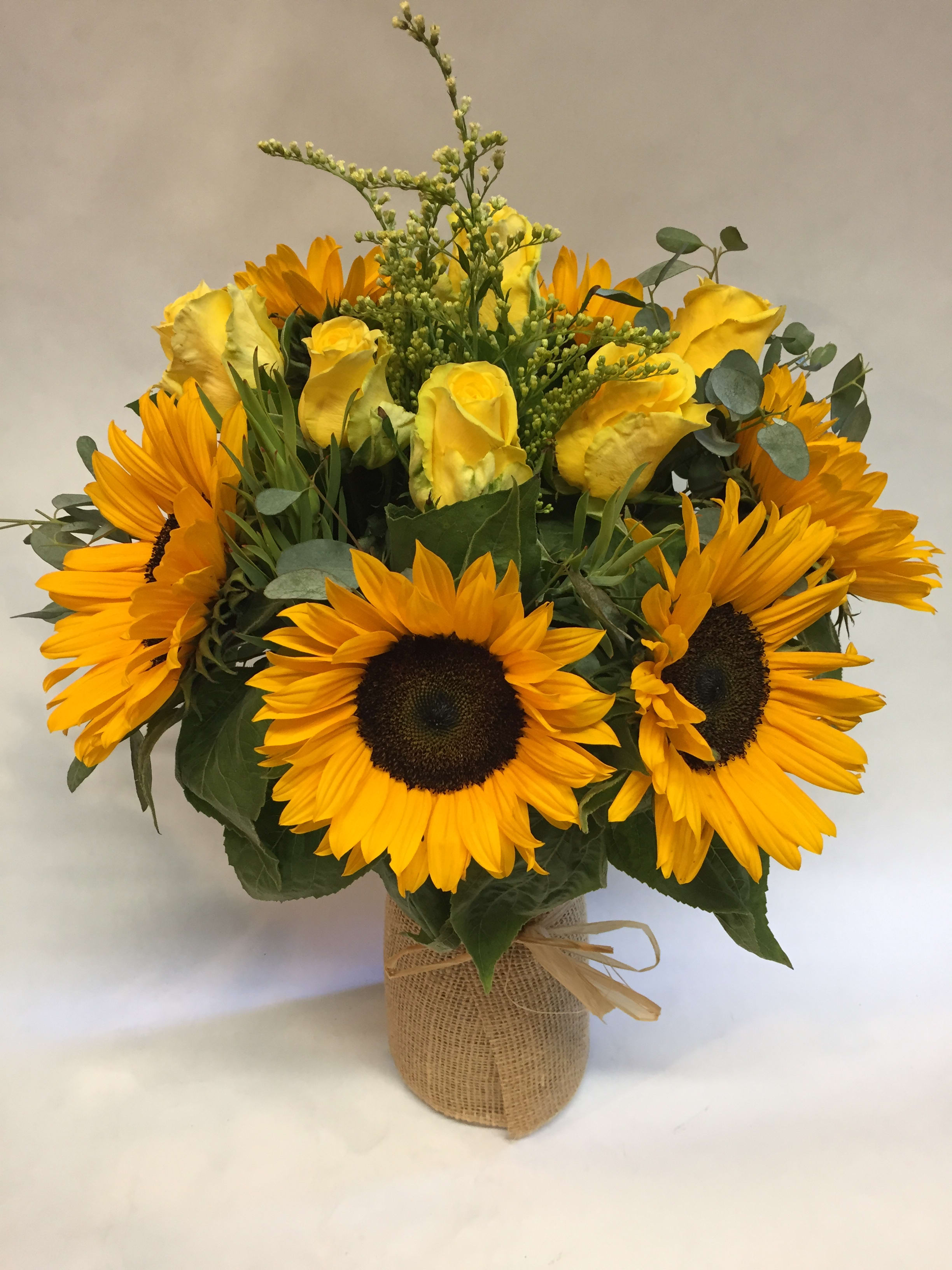 Bouquet of yellow roses and sunflowers in a burlap-wrapped vase