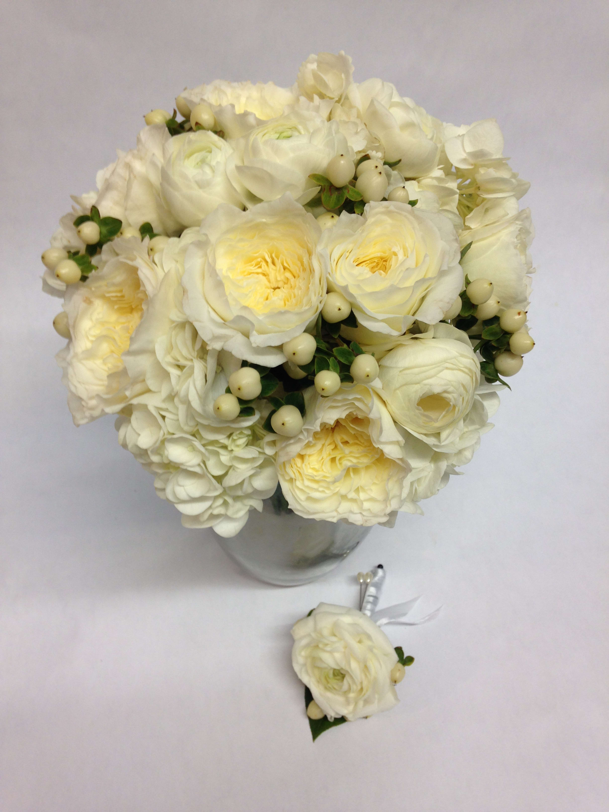White rose bouquet in a glass vase with a matching boutonniere below