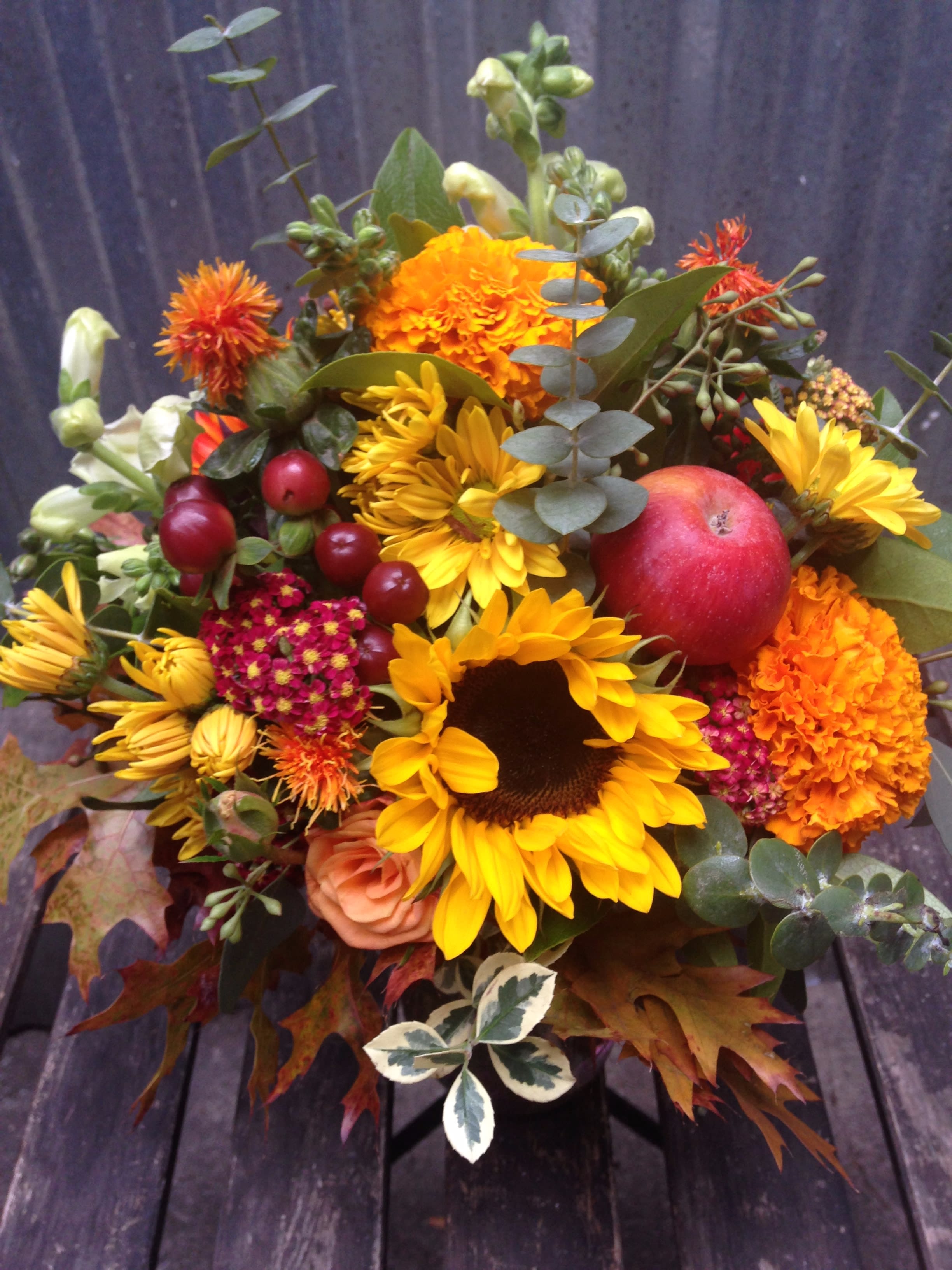 Autumn bouquet with sunflowers, marigolds, and a red apple