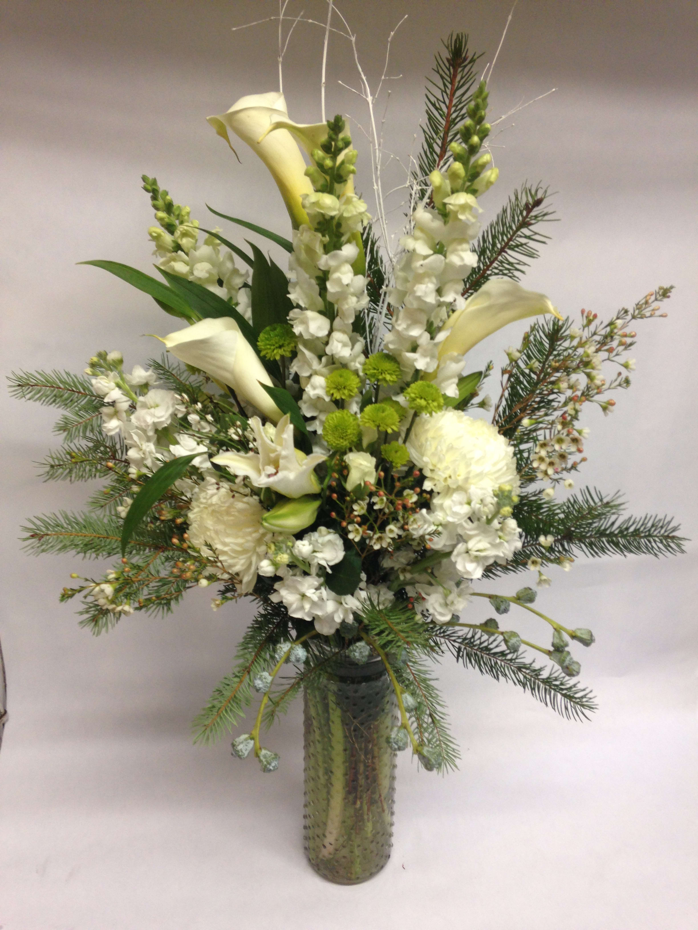 Tall white floral arrangement in a glass vase with calla lilies and snapdragons