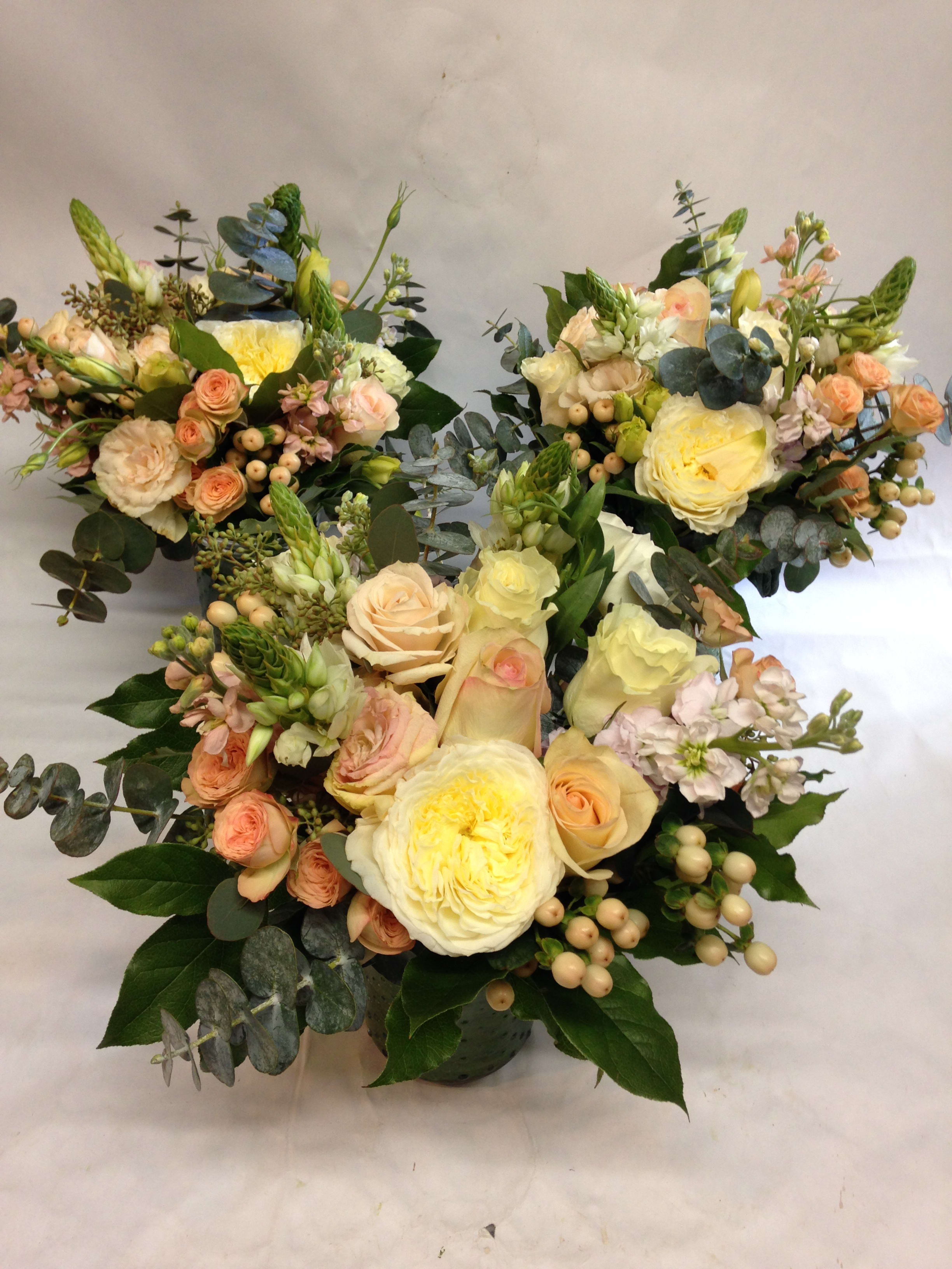 Three pastel floral bouquets with roses and eucalyptus on a white background
