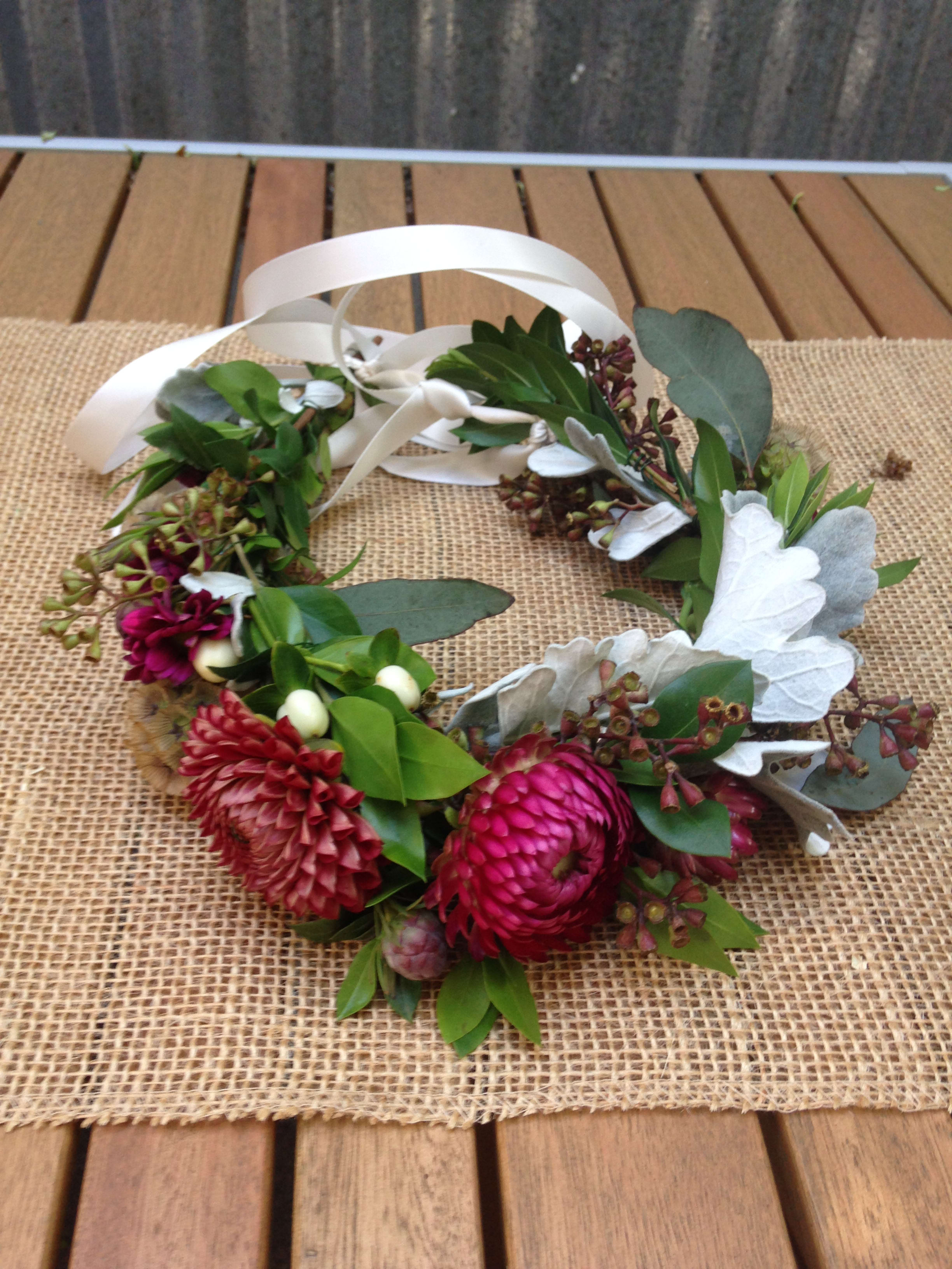 Floral wreath with pink blooms and white ribbon on a burlap mat