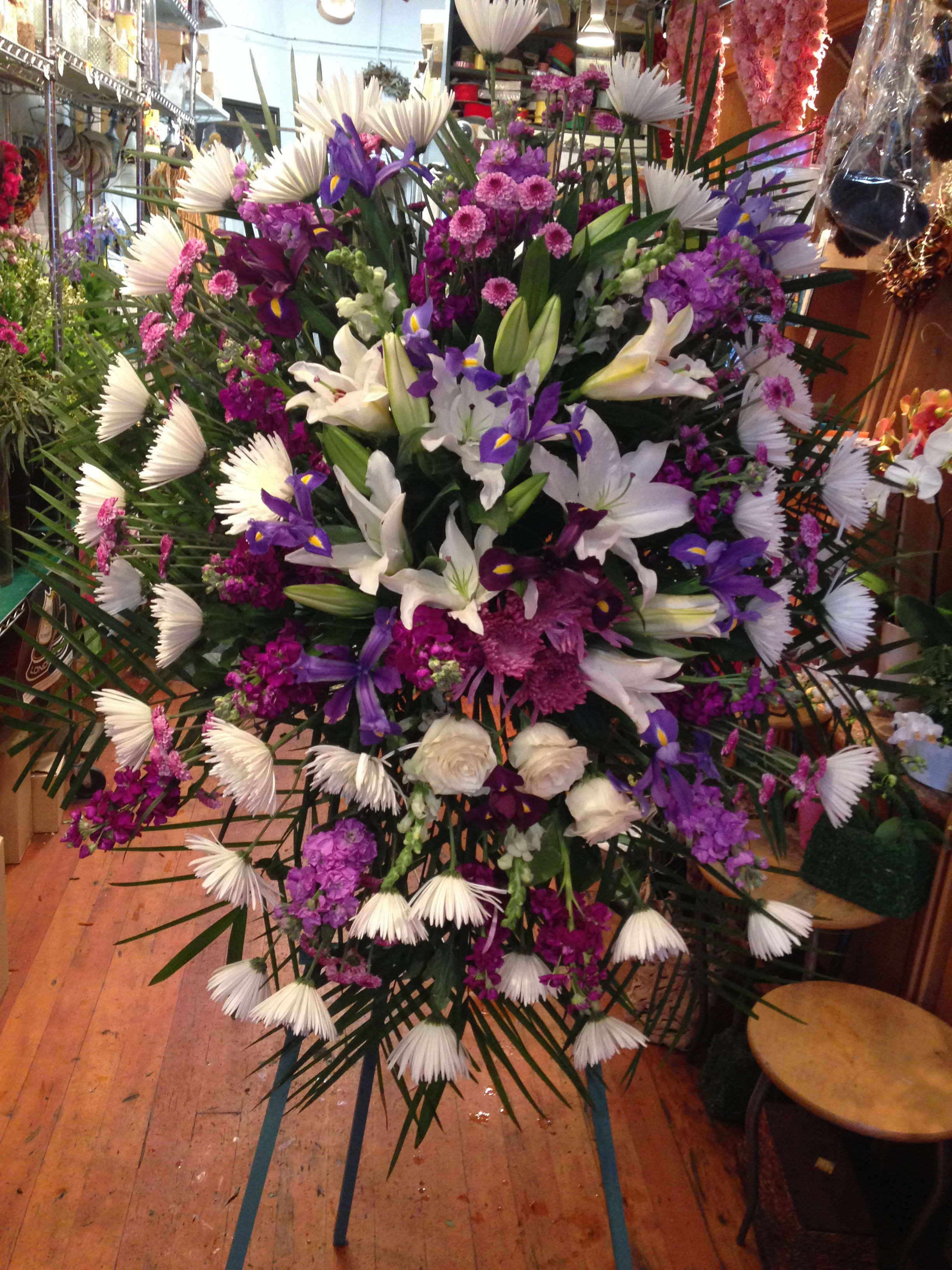 Large standing floral spray with white lilies, purple irises, and pink blooms