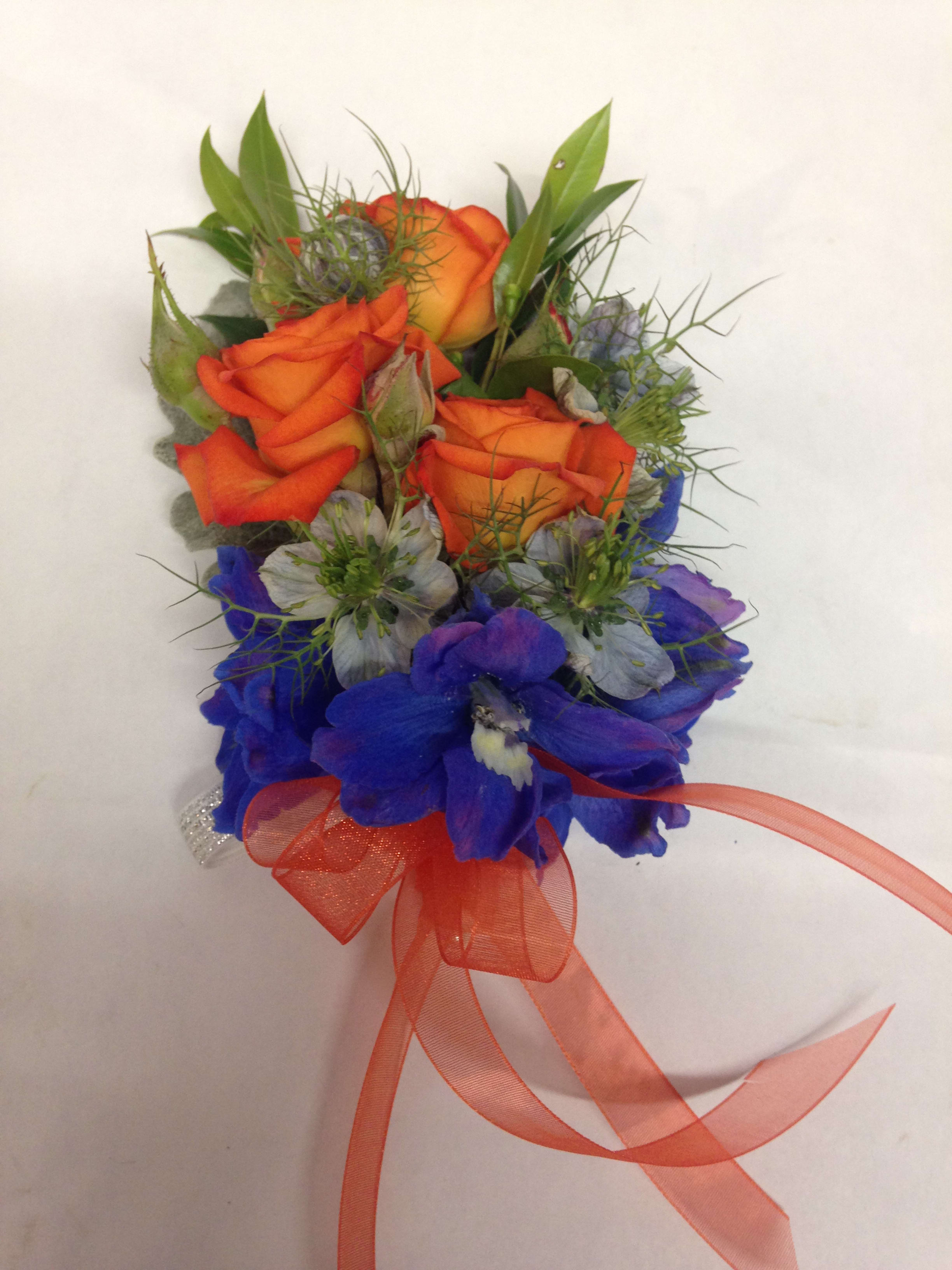 Orange roses with blue flowers and a ribbon bow
