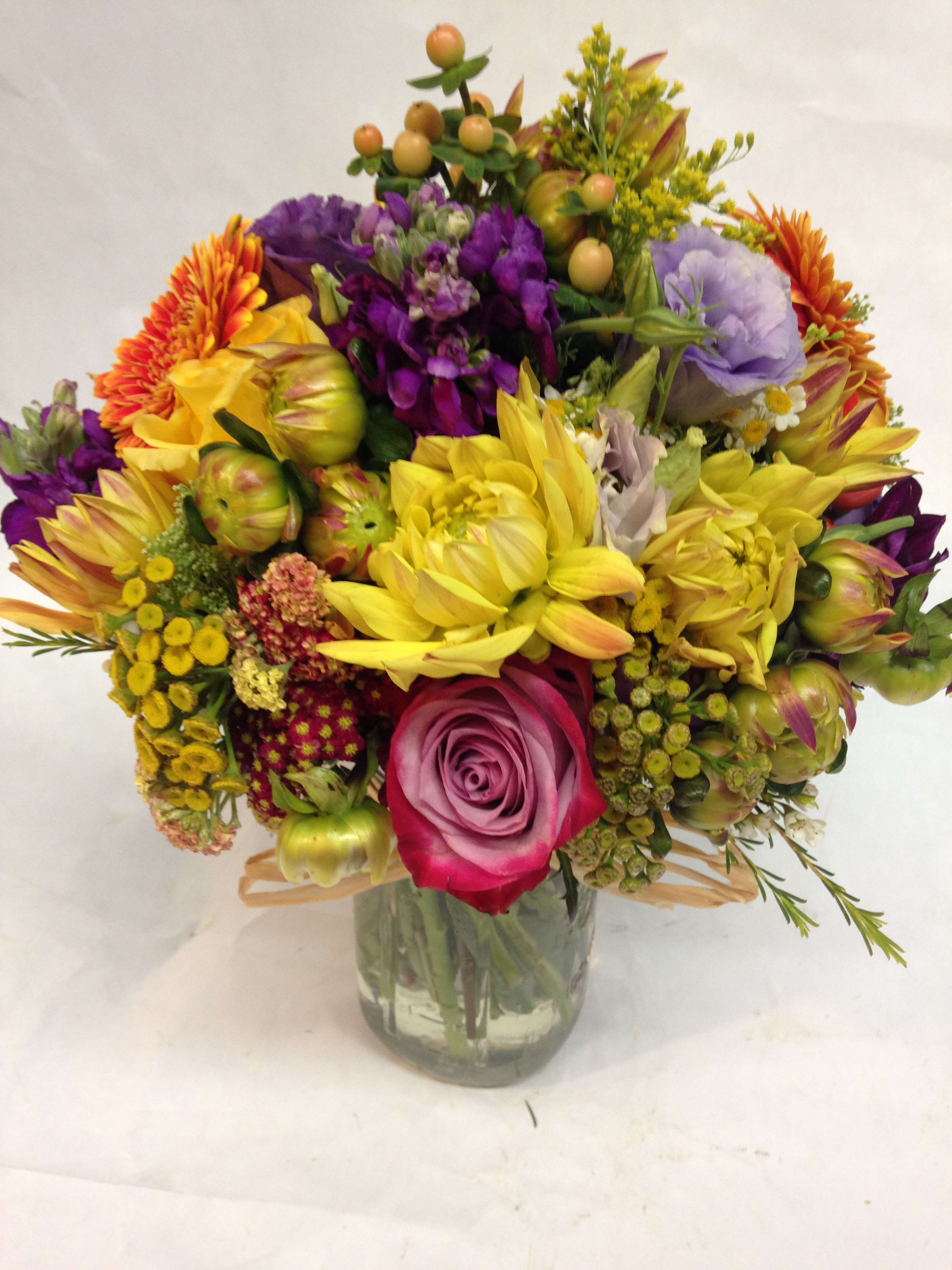 Colorful mixed bouquet in a clear glass vase with roses and daisies